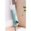Close-up of the top part of a spray mop, leaning against a wall and a wooden panel. Náhled obrázku produktu