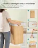 A person is assembling a bamboo laundry basket, with step-by-step instructions shown on the right side of the image. Produktbild-Vorschau