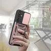A hand holding a rose gold phone case with a ring holder, with a blurred indoor background. Produktbild-Vorschau
