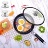 A cooking scene with a frying pan, eggs, shrimp, and various ingredients, along with a set of lid knobs. Produktbild-Vorschau
