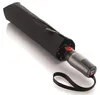 A closed black umbrella is lying on a white surface. Anteprima dell’immagine prodotto