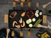A raclette grill with food being prepared on it, set on a wooden table. Produktbild-Vorschau