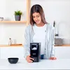 A woman is standing in a kitchen, operating a popcorn maker. Produktbild-Vorschau