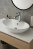 A white ceramic sink with a chrome faucet is shown on a light-colored countertop in a bathroom setting. Podgląd zdjęcia produktu