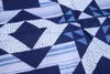 A close-up view of a blue and white patchwork quilt with geometric patterns. Produktbild-Vorschau