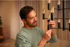 A man is installing a light bulb in a chandelier. Produktbild-Vorschau