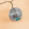 A single silver spherical lantern with intricate cutouts and a teal accent is shown against a plain light peach background. Produktbild-Vorschau