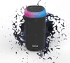 A black cylindrical Bluetooth speaker with a colorful LED light ring on top, surrounded by abstract black liquid splashes. Voir les images du produit