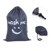A gray laundry bag with a smiley face and the words "wash me" printed on it, shown with close-up details of the drawstring closure. Produktbild-Vorschau