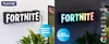 A split image showing a Fortnite logo light mounted on a wall. The left side shows the light in white, and the right side shows it illuminated with RGB colors. Anteprima dell’immagine prodotto