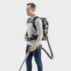 A man wearing a backpack vacuum cleaner and holding its wand. Produktbild-Vorschau
