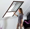 A woman is adjusting a screen on a skylight window in an attic room. Produktbild-Vorschau