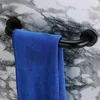A black grab bar mounted on a marble-patterned wall, with a blue towel draped over it. Produktbild-Vorschau