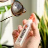 A hand holding a bottle of WHOOSH screen cleaner near dirty sunglasses. Anteprima dell’immagine prodotto
