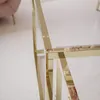 A close-up view of the corner of a gold metal framed coffee table with a clear glass top. Produktbild-Vorschau