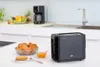 A black Braun toaster sits on a white countertop next to a bowl of croissants and a small bowl of jam. Anteprima dell’immagine prodotto