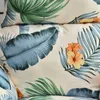 A close-up view of a fabric with a tropical leaf and flower pattern. Produktbild-Vorschau