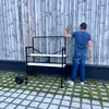 A person is standing next to a black and white rolling scaffold with two shelves. Anteprima dell’immagine prodotto