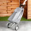 A person's hand is holding the handle of a gray shopping trolley, which is positioned on a concrete path with a wooden fence and artificial grass in the background. Anteprima dell’immagine prodotto