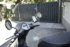 A scooter with a phone mount attached to the handlebars, parked in front of a gate. Anteprima dell’immagine prodotto