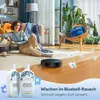 A woman relaxing in a living room while a robot vacuum cleans the floor. Produktbild-Vorschau