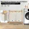 A bamboo laundry basket with two compartments next to a washing machine. Voir les images du produit