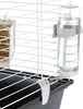 A close-up view of a pet cage accessory, specifically a water bottle and a hay feeder, attached to the cage bars. Náhľad obrázku produktu