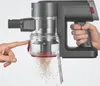 A hand presses a button on a handheld vacuum cleaner, causing dust to fall out of its transparent bin. Produktbild-Vorschau