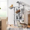 Three cats are interacting with a large, multi-level cat tree in a living room setting. Produktbild-Vorschau