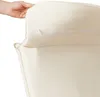 A hand is shown pulling the cream-colored fabric of a cushion, revealing a zipper. Náhled obrázku produktu