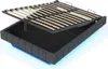 A bed frame with its mattress support lifted, revealing storage space underneath. The frame is upholstered in dark gray fabric and has blue LED lighting around its base. Podgląd zdjęcia produktu