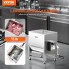 A stainless steel meat grinder with text overlays highlighting its features and dimensions, set against a blurred background of a commercial kitchen. Náhľad obrázku produktu