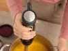A person is using an immersion blender in a pot of yellow soup. Produktbild-Vorschau
