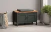 A dark green storage bench with a wooden top and a gray cushion sits on a rug in a room. A woven basket with a gray blanket is to the left, and a large potted plant is to the right. Anteprima dell’immagine prodotto