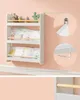 A white three-tiered wall-mounted bookshelf for children's items, with books and toys on display. Náhled obrázku produktu