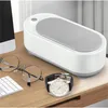A white ultrasonic cleaner sits on a wooden desk next to a pair of glasses and a watch. Voir les images du produit
