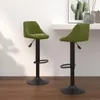 Two green bar stools are shown in a room with a white wall and wooden floor. Náhled obrázku produktu