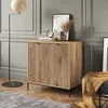 A modern living room setting with a wooden cabinet, floor lamp, rug, and artwork. Produktbild-Vorschau