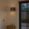 An outdoor wall light illuminates a doorway and a small wooden cabinet at dusk. Produktbild-Vorschau