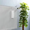 A white ceramic air humidifier with a floral pattern hangs from a white radiator next to a green plant. Podgląd zdjęcia produktu
