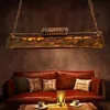 A vintage-style pendant light fixture hangs above a red leather sofa with decorative pillows and a coffee table with cups and a candle. Produktbild-Vorschau