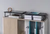 A monitor stand is placed on top of a bookshelf, holding a laptop and a tablet. Books are visible on the shelf below. Náhled obrázku produktu