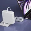A white MacBook charger plugged into a wall socket, connected to a MacBook. Produktbild-Vorschau