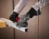 A person wearing black gloves is using a cordless angle grinder to cut a metal bar. Produktbild-Vorschau