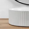 A close-up shot of a white, fluted basin on a wooden surface. Podgląd zdjęcia produktu