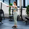 A woman is performing a dumbbell exercise in a gym. Produktbild-Vorschau