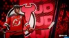 A hockey player in a red jersey stands with a hockey stick against a backdrop of red and black graphics. Produktbild-Vorschau
