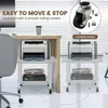 A printer stand with a printer on it, shown in two different positions next to a desk, with text overlays highlighting its features. Produktbild-Vorschau