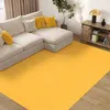 A living room scene with a sectional sofa, a large yellow rug, and a wooden media console. Náhľad obrázku produktu