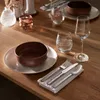 A table setting with plates, bowls, cutlery, and glasses. Produktbild-Vorschau